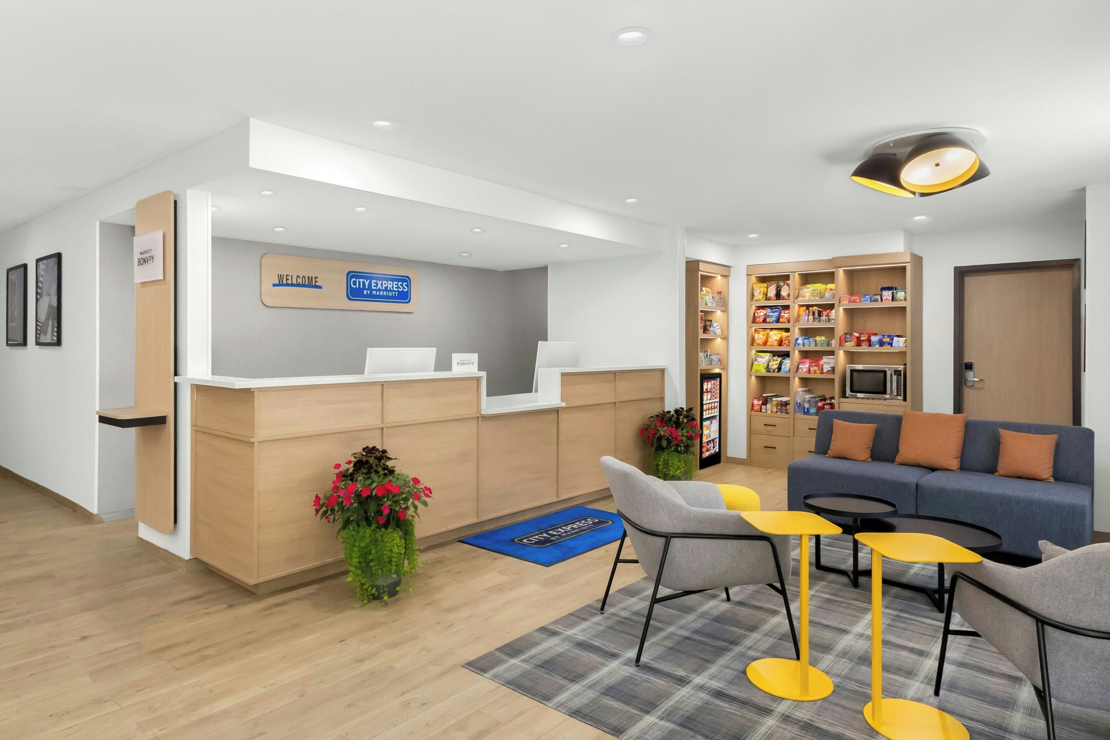 A hotel reception area with a reception desk, seating area, and a kitchenette.