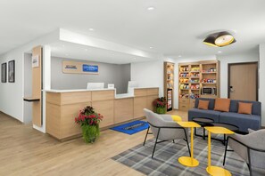 Zona de recepción de hotel con mostrador, área de descanso y kitchenette.