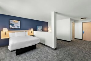 Habitación de hotel con cama, dos lámparas de noche, cabecero, obra de arte en la pared y una puerta.