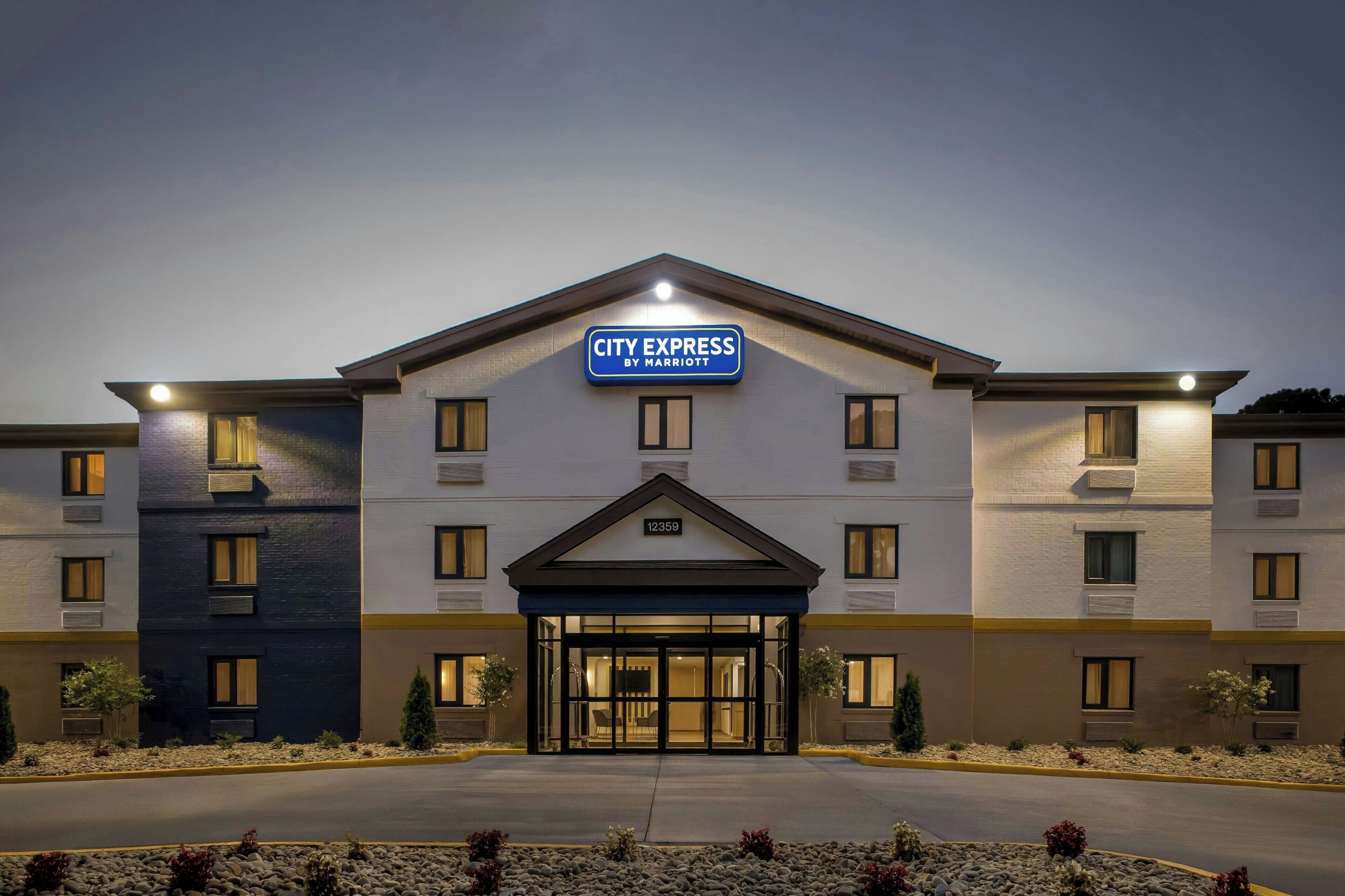 A CITY EXPRESS hotel with a modern design, featuring a prominent entrance and a clear address sign.