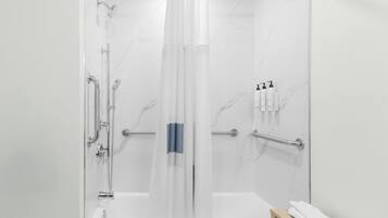 A modern bathroom with a glass-enclosed shower, a bathtub, and a handrail.