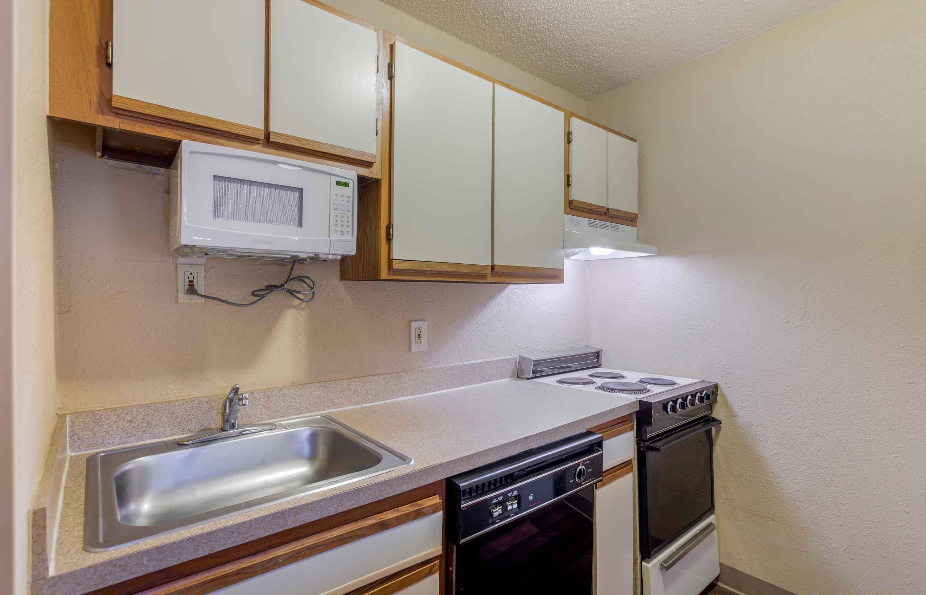 Cocina compacta con microondas, estufa, pileta y lavavajillas.