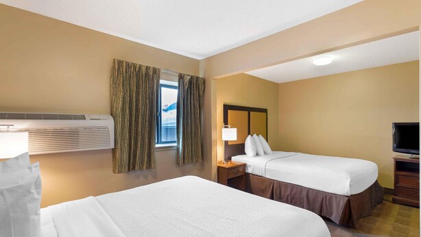 A hotel room with two beds, a TV, a lamp, and a window with curtains. - Extended Stay America Select Suites Richmond Innsbrook (Glen Allen)
