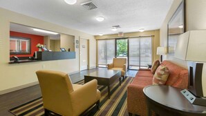 A hotel lobby with a reception desk, seating area, and a large window with blinds. - Extended Stay America Suites Toledo Maumee (Maumee)