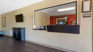Un'area reception con una scrivania, un cartello con la scritta 'Welcome', un quadro incorniciato e un mobiletto.