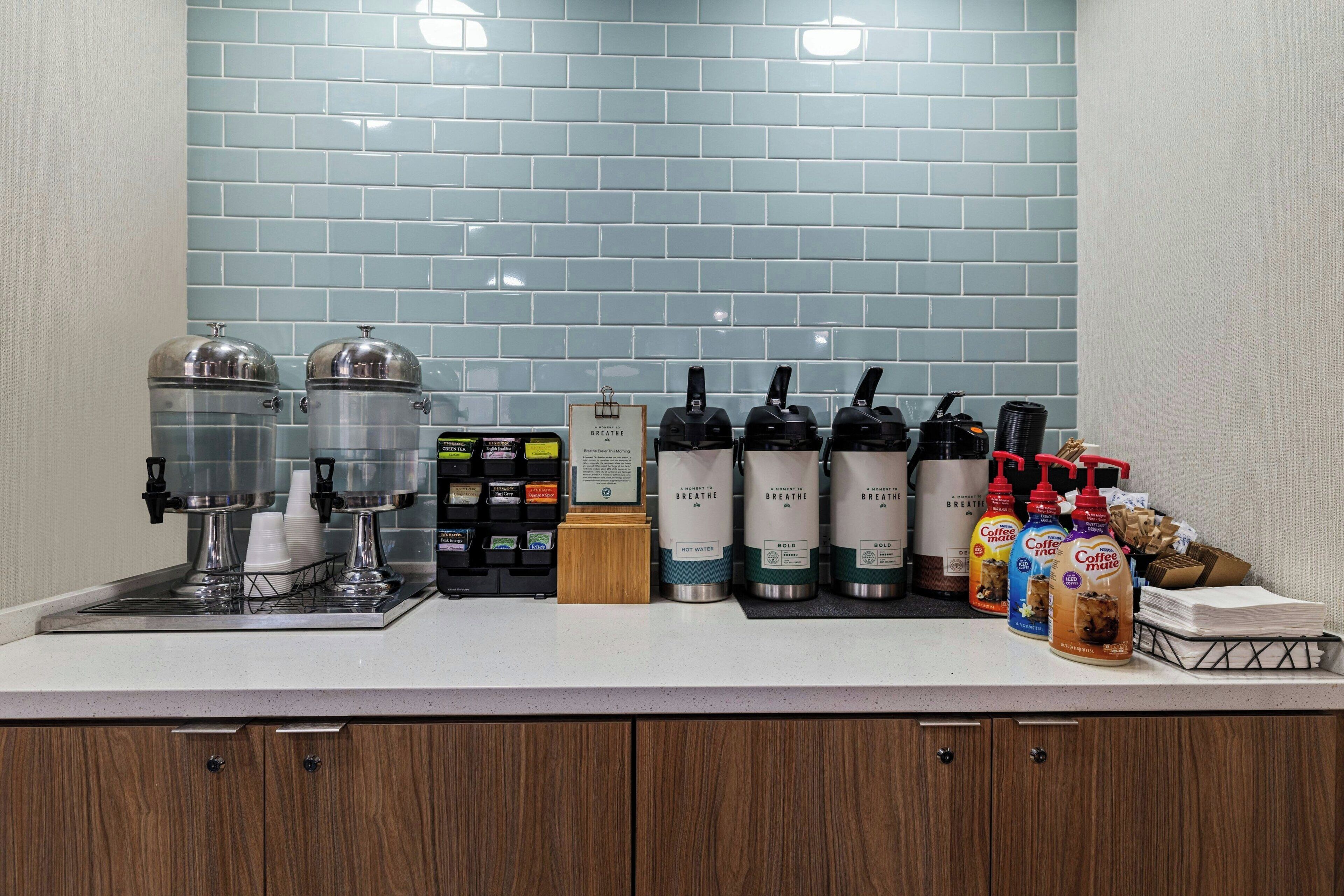 A coffee station with dispensers, a coffee machine, and a menu board.