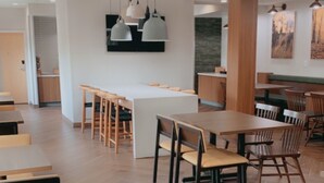 A modern dining area with wooden tables and chairs, a central island, and pendant lighting. - Fairfield Inn & Suites by Marriott Lake Charles Sulphur (Sulphur)