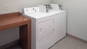 A compact, white front-loading washer and dryer unit with a wooden countertop on the left.