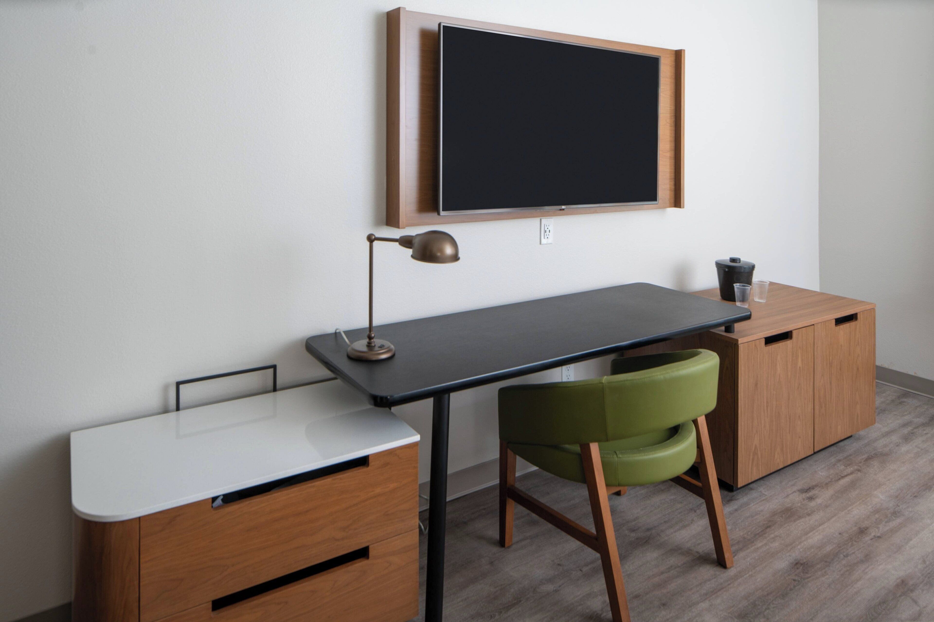 A modern study area with a desk, chair, and a mounted television.