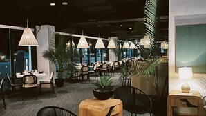 A modern lounge area with multiple seating arrangements, including sofas and chairs, a central wooden planter, and ambient lighting. - Fenwick Inn (Ocean City)