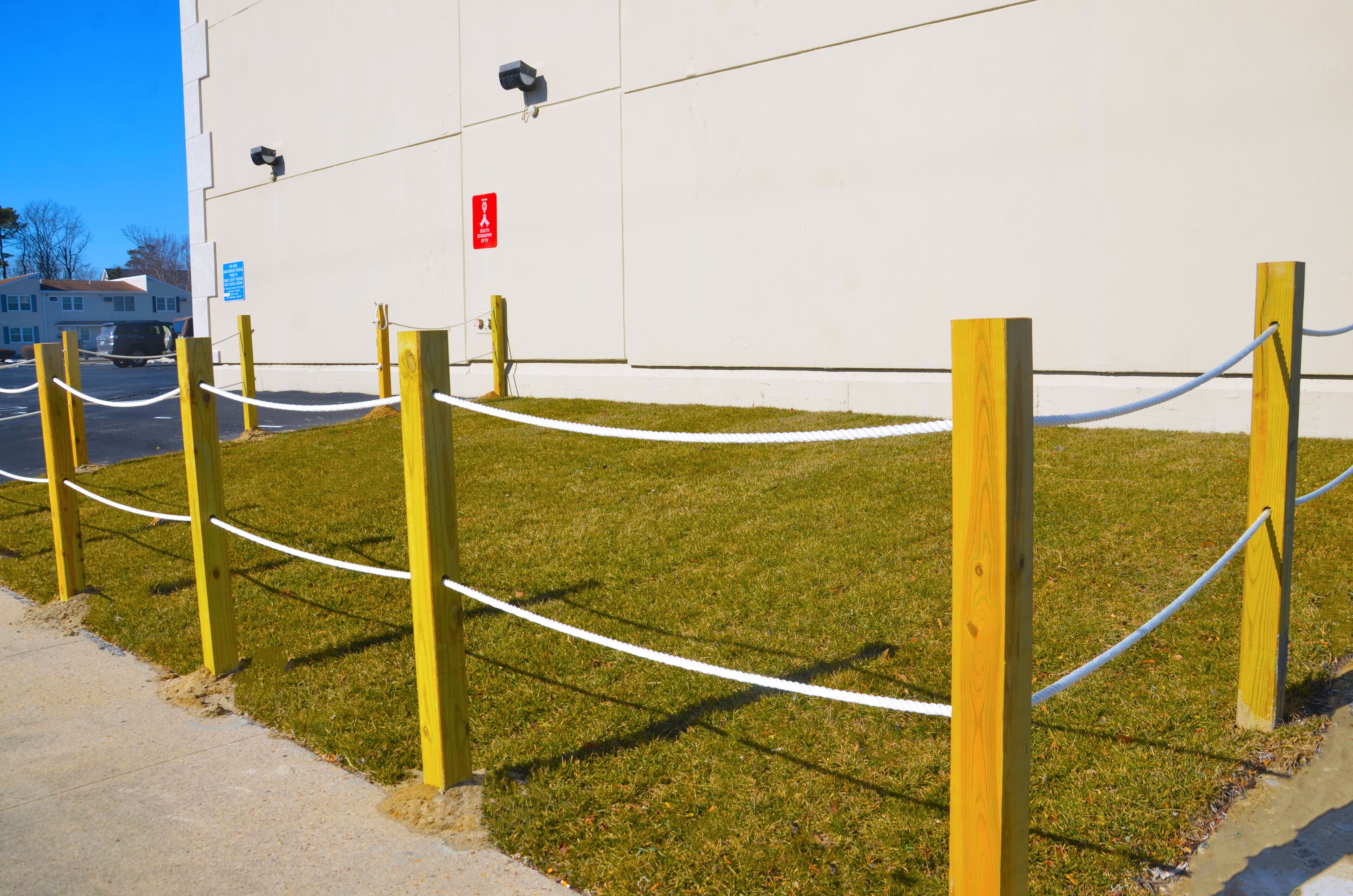 A fenced grassy area with a white building in the background.