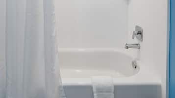 Un baño moderno con una bañera blanca, una cortina de ducha y un cabezal de ducha manual.