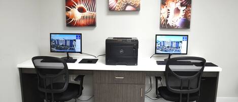 A modern office desk with two monitors, a printer, and two office chairs.