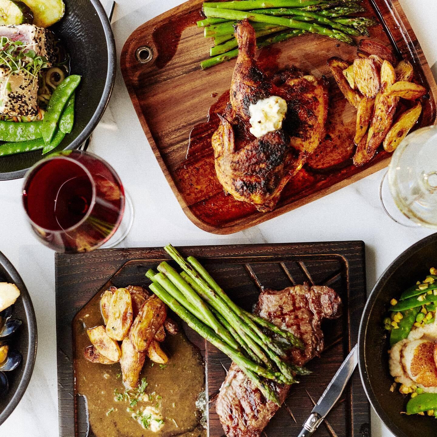 A meal with grilled meat, asparagus, and potatoes on a wooden board.