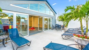 A modern house with a glass door entrance, outdoor seating area with chairs, and a small table. - Fenwick Inn (Ocean City)