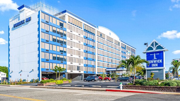 A multi-story hotel with a prominent blue and white facade, a parking garage, and a clear blue sky.