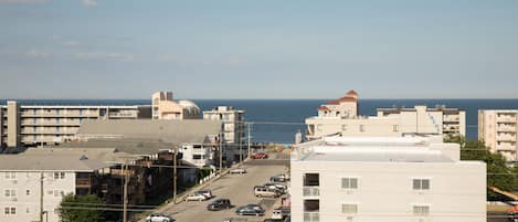Una calle urbana costera con edificios, vehículos y una vista despejada del mar.