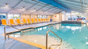 A swimming pool with multiple lanes, sun loungers, and a covered area with chairs.