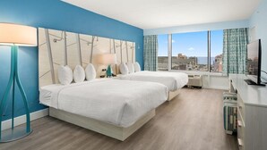 A hotel room with two beds, a large window with a city view, a flat-screen TV, and a desk with a lamp. - Fenwick Inn (Ocean City)