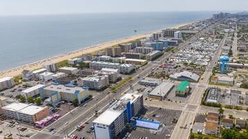 Une vue aérienne d’une ville côtière, avec une plage, des immeubles commerciaux et un parking.