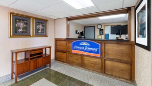 A reception desk with a sign for Howard Johnson Inn, a clock, and framed floral artwork on the wall. - Howard Johnson by Wyndham Gillette (Gillette)