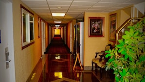 A hotel hallway with a long corridor, a red carpet, and a potted plant. - Howard Johnson by Wyndham Gillette (Gillette)