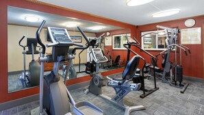 A fitness center with various exercise machines, a large mirror, and a clock on the wall. - Howard Johnson by Wyndham Gillette (Gillette)