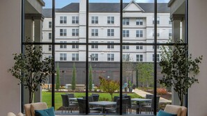 A room with a large arched window, two beige armchairs with blue cushions, a round coffee table, and a patterned rug. - Residence Inn by Marriott Atlanta Buckhead (Atlanta)