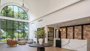 A spacious lobby with a round table, sofas, a reception desk, and large windows offering a view of trees. - Residence Inn by Marriott Atlanta Buckhead (Atlanta)