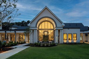 A modern house with a large arched window, a well-maintained lawn, and a patio area.