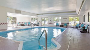 Una piscina interna con zona acqua cristallina, una scala di metallo e diverse poltrone prendisole intorno alla piscina.