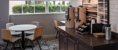 Una cocina moderna con un espacio para café, una mesa redonda con sillas y vistas al exterior.