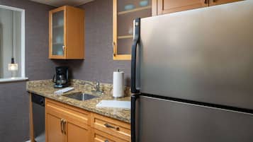 A kitchen with granite countertops, stainless steel appliances, wooden cabinets, and a built-in dishwasher.