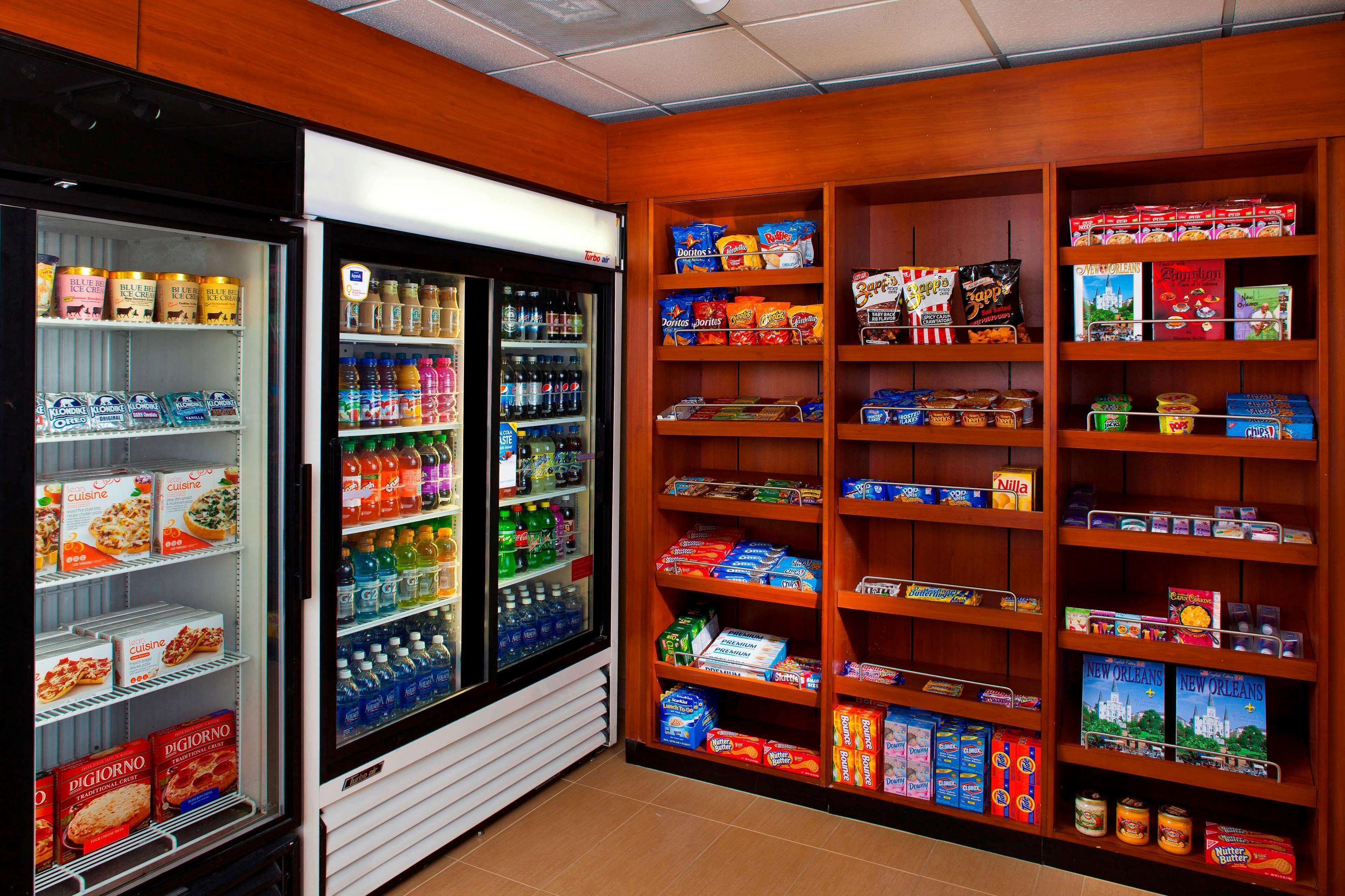 A refrigerated display case with various food items and a shelf stocked with snacks and beverages.