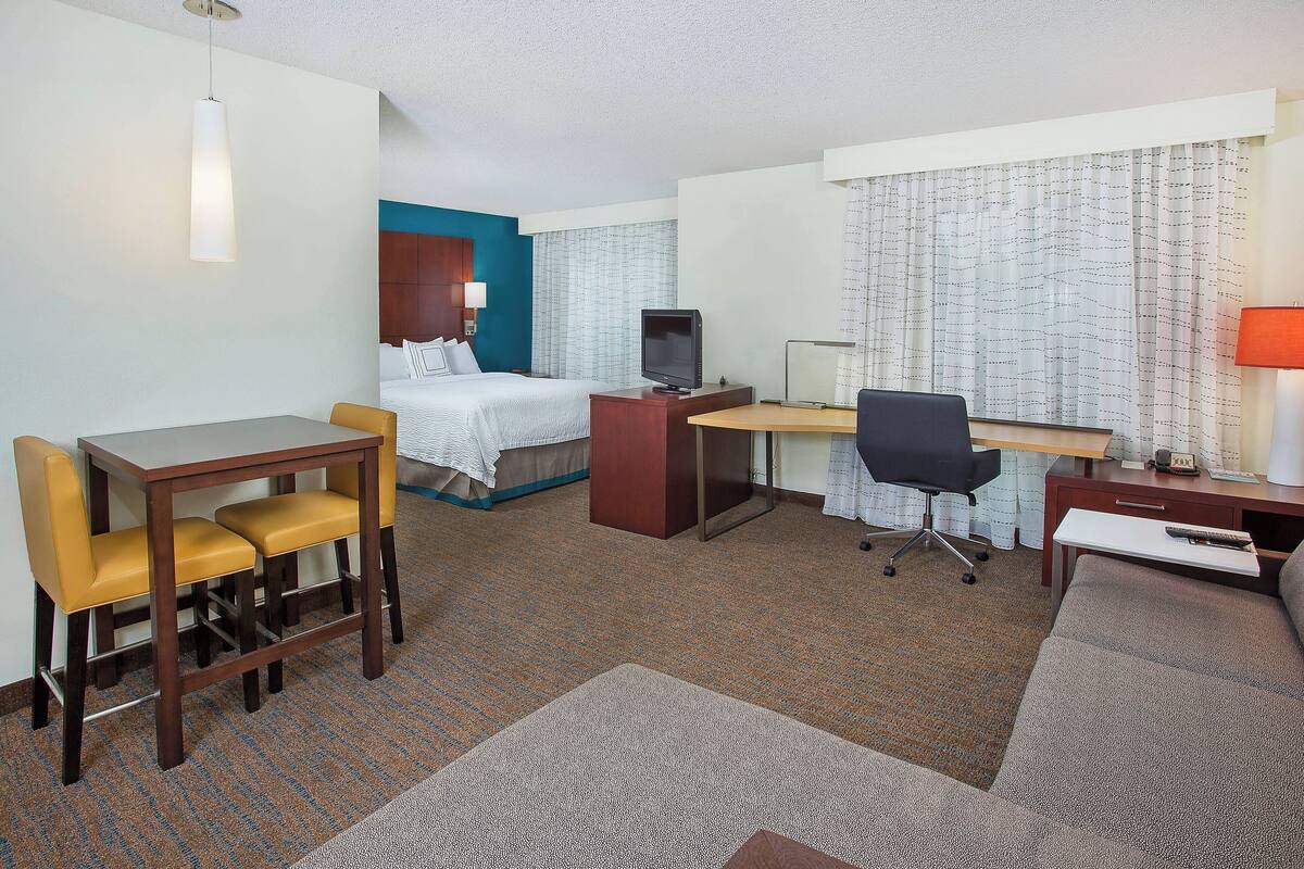 Ein Hotelzimmer mit Bett, Schreibtisch, Stuhl, Fernseher und Lampe.