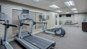 Un gimnasio con cintas de correr, elípticas y un dispensador de agua.