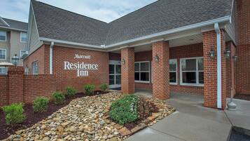 A Marriott Residence Inn with a brick facade, a covered entrance, and a landscaped area with rocks and shrubs.