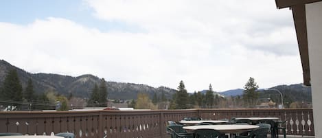 An outdoor patio with tables and chairs, a decorative fence, and a mountainous backdrop.