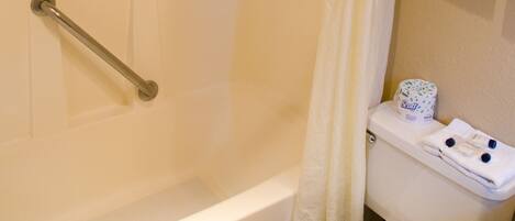 A bathroom with a bathtub, toilet, and shower curtain.