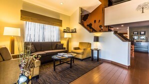 A modern hotel lobby with a sofa, armchairs, a coffee table, and a staircase. - Sleep Inn Springfield South I60 near Medical District (Springfield)