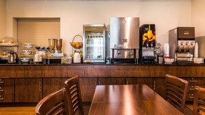 A kitchen with a wooden table and chairs, a coffee machine, a fruit juicer, and a refrigerator. - Sleep Inn Springfield South I60 near Medical District (Springfield)
