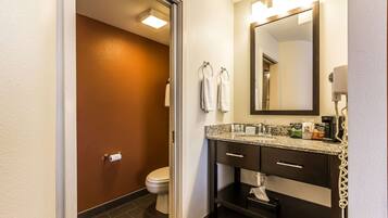A bathroom with a toilet, a sink with a mirror, and a towel rack.