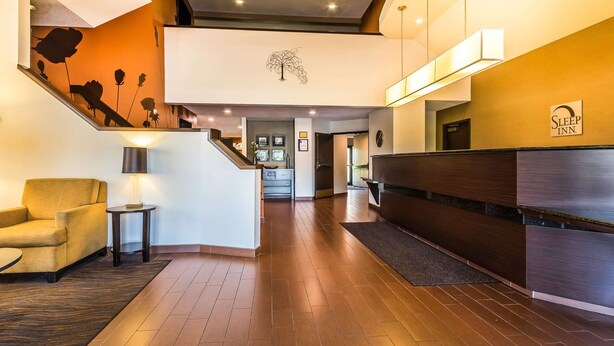 A hotel lobby with a reception desk, a staircase, and a seating area. - Sleep Inn Springfield South I60 near Medical District (Springfield)