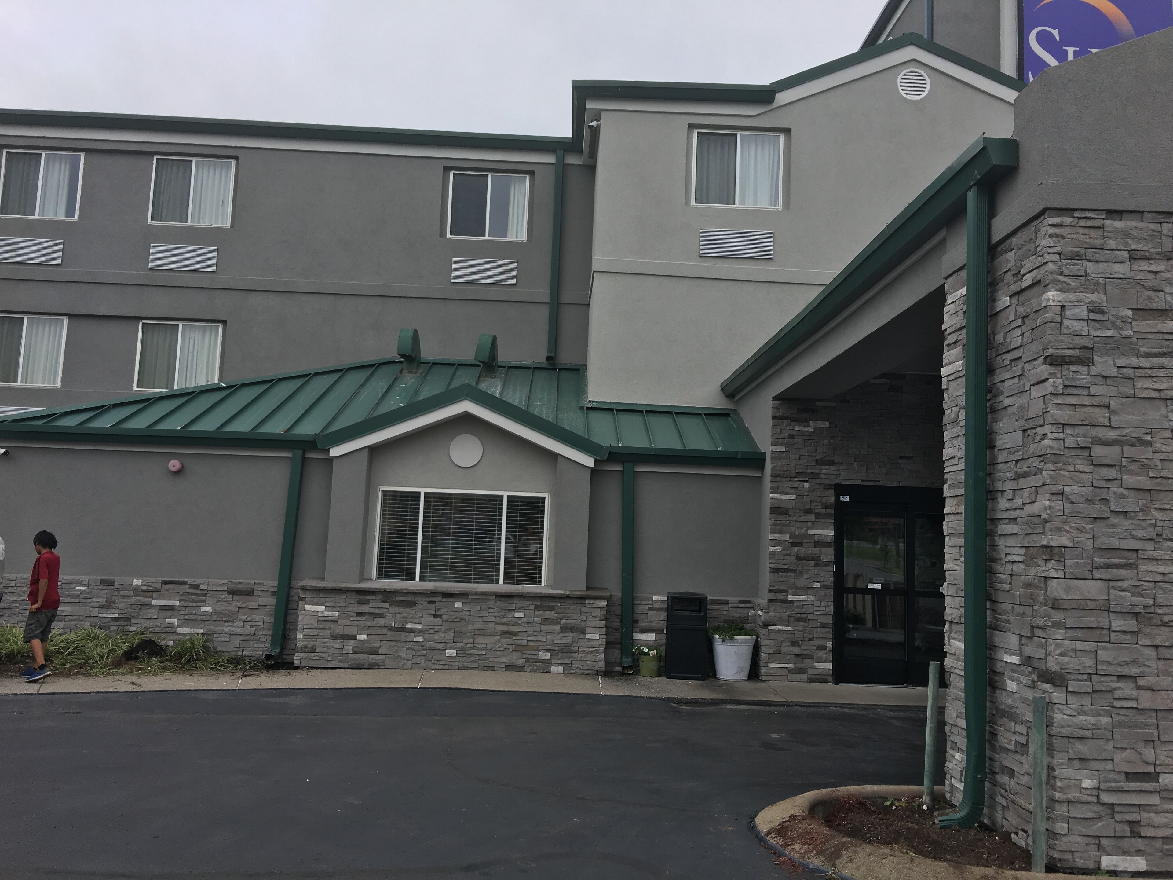 A building with a green roof, stone facade, and a black door.