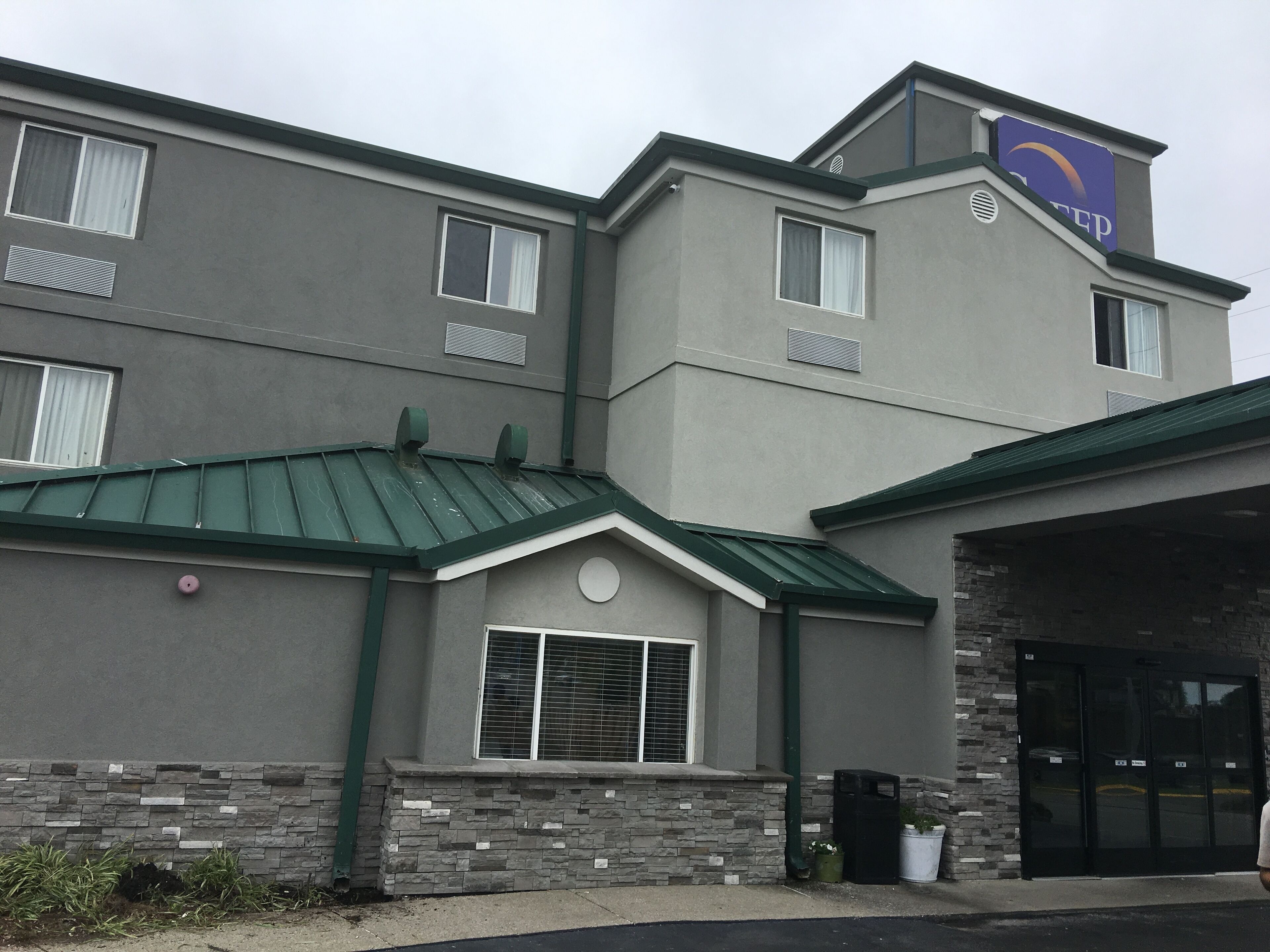 Um hotel com fachada de pedra, telhado verde e uma placa indicando ser um Fairfield Inn & Suites.