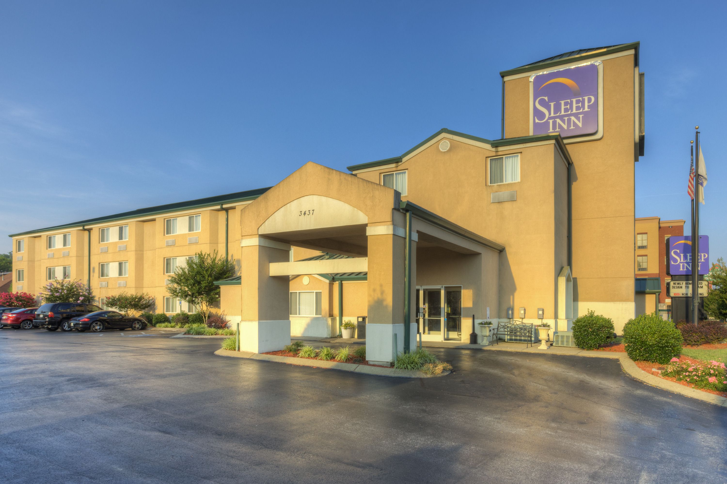 Un hotel Sleep Inn con una entrada amplia, un estacionamiento y un asta de bandera.