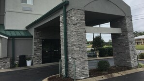 Um hotel Sleep Inn com entrada em arco de pedra, um letreiro acima da entrada e um estacionamento em primeiro plano.