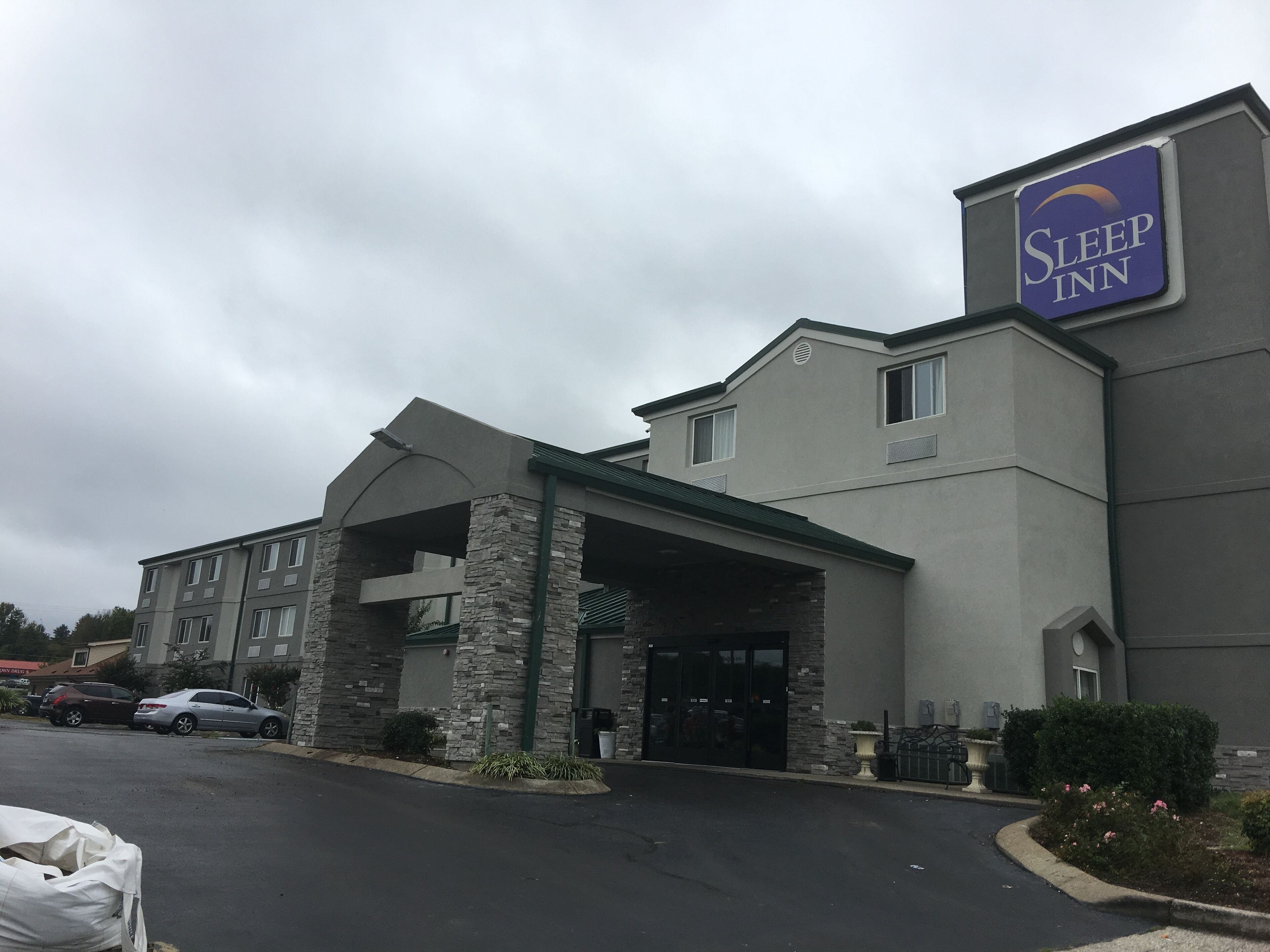 Un hotel Sleep Inn con fachada de piedra, varias ventanas y un estacionamiento.