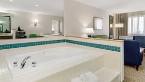 A hotel bathroom with a large bathtub, a mirror, a sink, and a chair. - Quality Inn & Suites Denver Airport - Gateway Park (Aurora)
