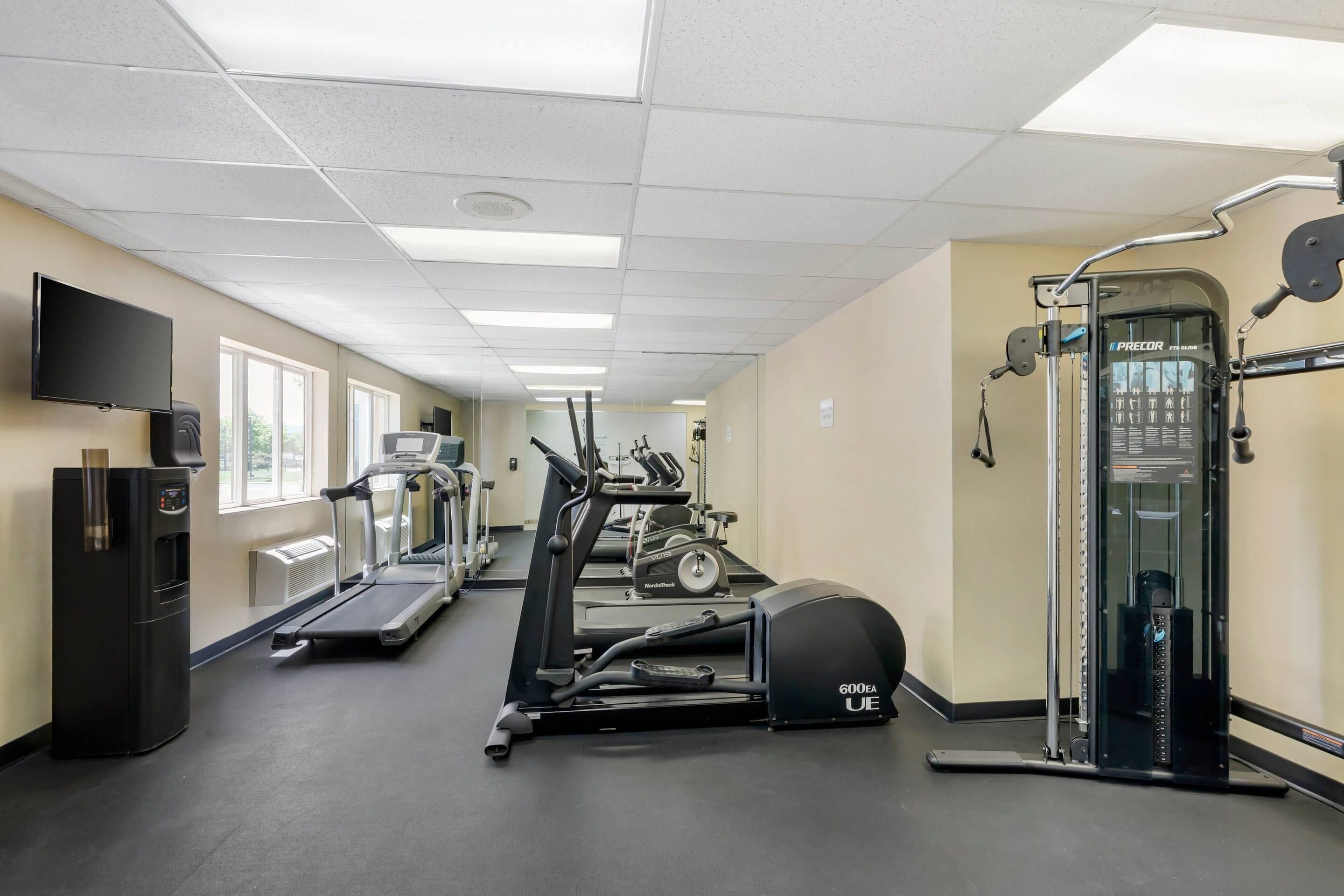A gym with treadmills, elliptical machines, and a weight machine.